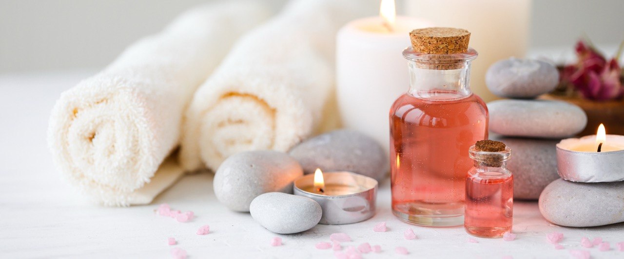 Wellnessambiente mit Handtüchern, Massageöl, Steinen und Kerzen